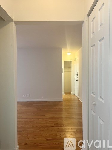 A hallway with wooden floors and white walls.