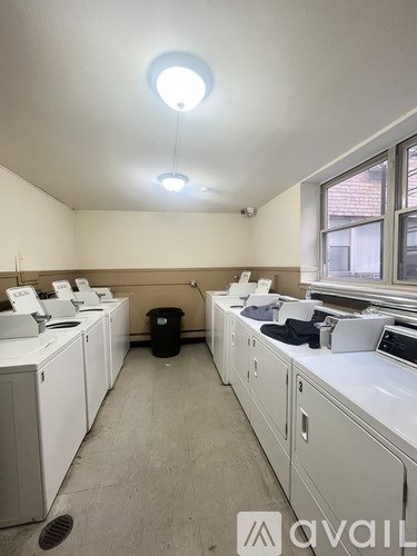 A room with white washing machines and a black trash can.