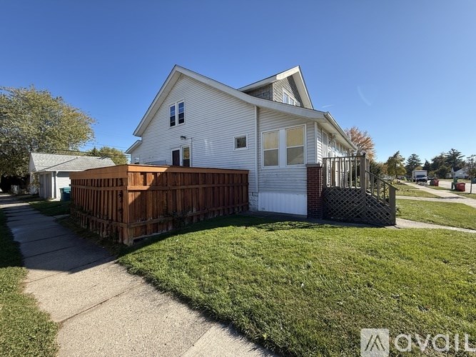 A white house with a brown fence and a small porch.