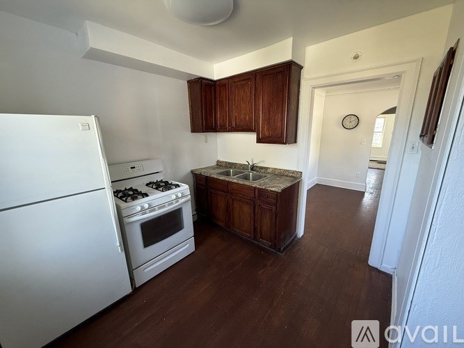 A kitchen with a white refrigerator, a white stove, and wooden cabinets.