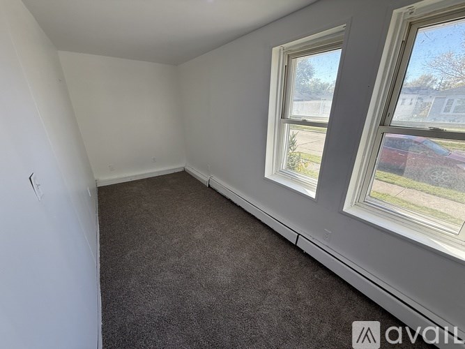 A room with a carpeted floor and two windows.