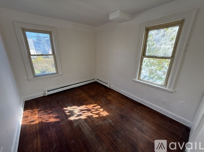 A room with wooden floors and two windows.