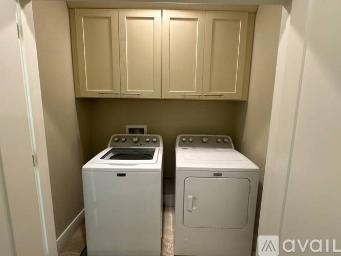 Two white front loading washing machines in a small laundry room.