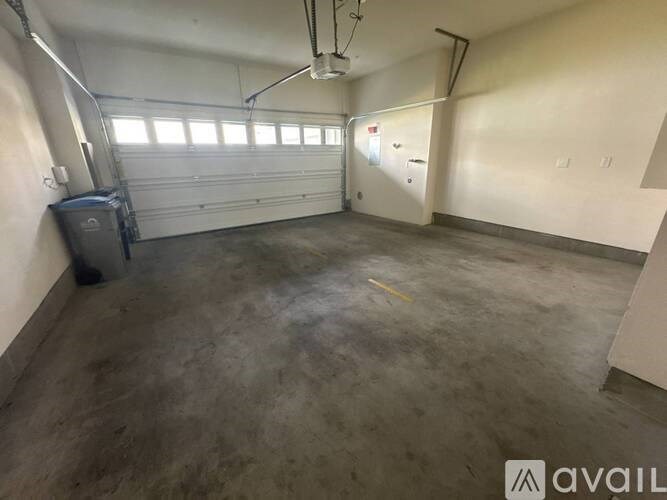 A large empty garage with a trash can and a window.