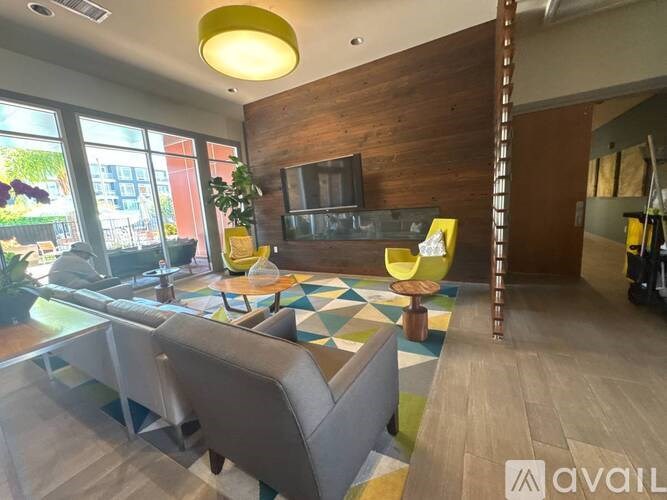 A living room with a grey couch and a wooden wall.