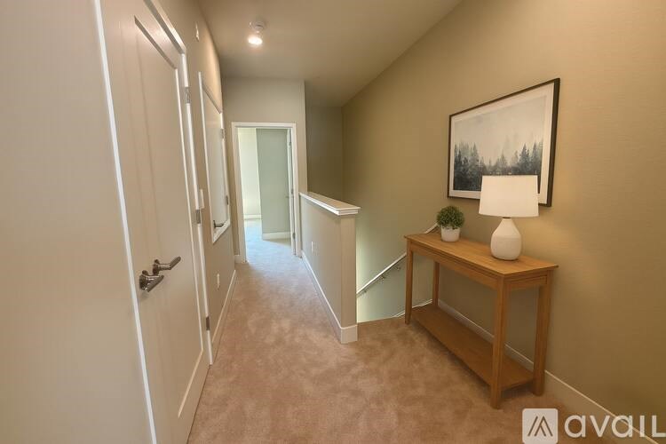 A hallway with a lamp and a painting on the wall.