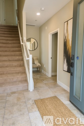 A hallway with a staircase and a mirror on the wall.