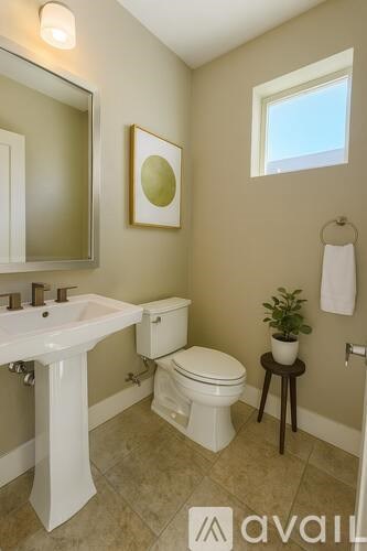 A bathroom with a toilet, sink, mirror, and a plant.