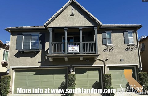 A house with a balcony and a sign that says "For Sale".