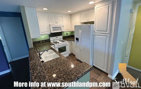 A kitchen with granite countertops and white cabinets.