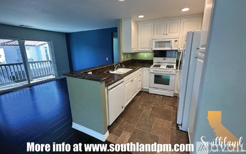 A kitchen with white cabinets and a black countertop.