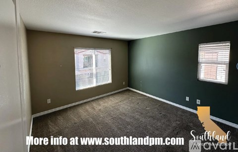 A room with a carpeted floor and two windows with blinds.