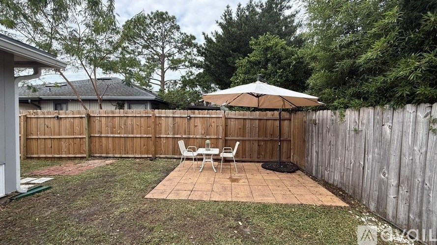 A patio with a table and chairs and an umbrella.