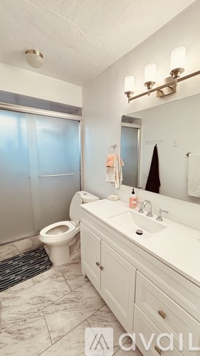 A bathroom with a toilet, sink, and mirror.