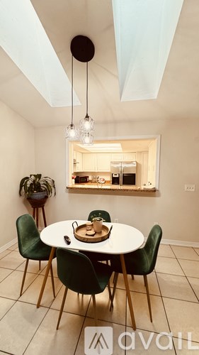 A dining room with a table set for two and a potted plant.