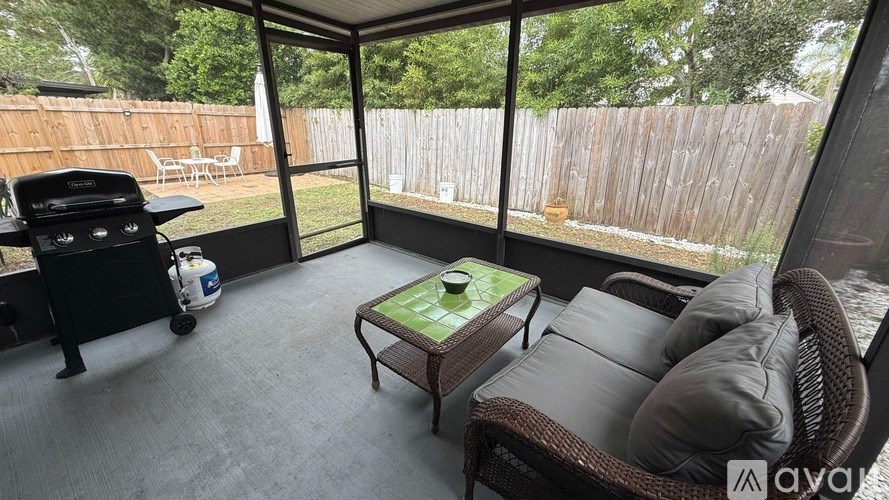 A patio with a wicker sofa and a coffee table.