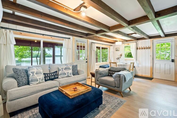 A living room with a grey couch, a blue ottoman, and a wooden coffee table.