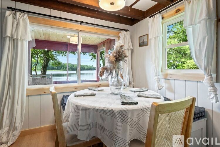 A dining table set in a room with a window overlooking a field.