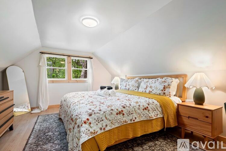 A bedroom with a bed, nightstand, and window.