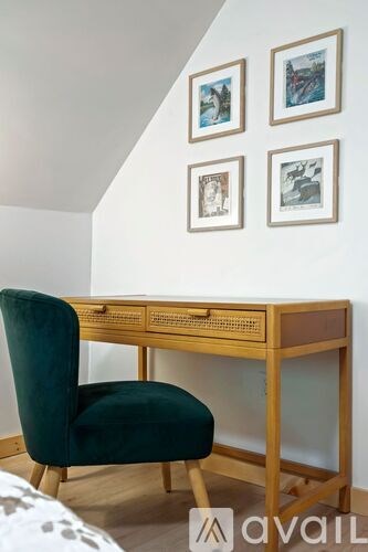A green chair sits in front of a wooden desk with a drawer.