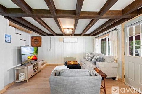 A living room with a grey couch and a wooden ceiling.