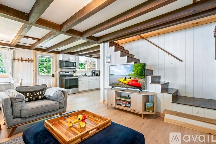 A living room with a grey couch, a wooden coffee table, and a television on a stand.