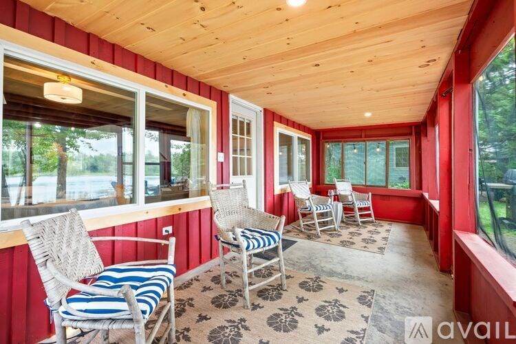 A sunroom with red walls and a wooden ceiling has a table and chairs.