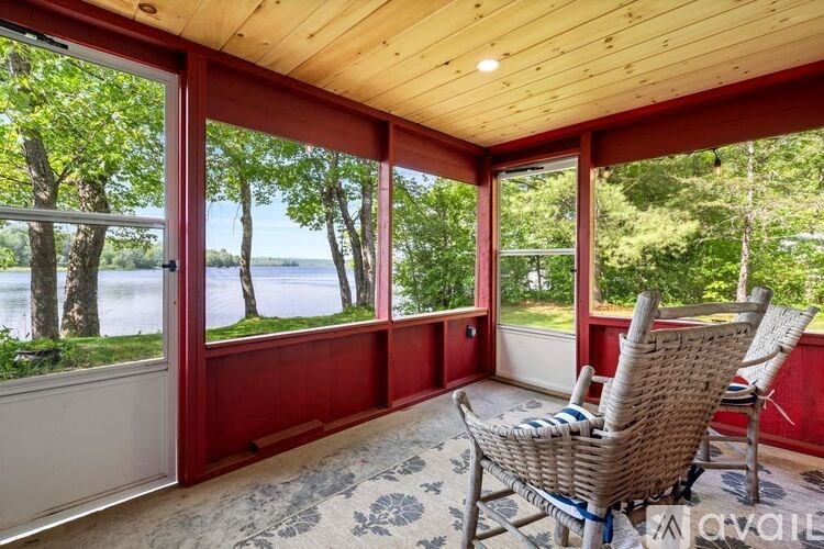 A wicker chair is placed in a room with a view of a lake.