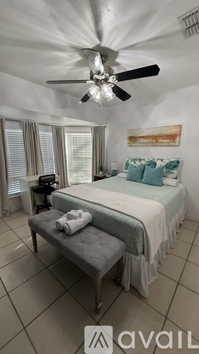 A bedroom with a bed, a ceiling fan, and a window with blinds.