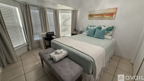 A bedroom with a bed, a bench, and a painting on the wall.