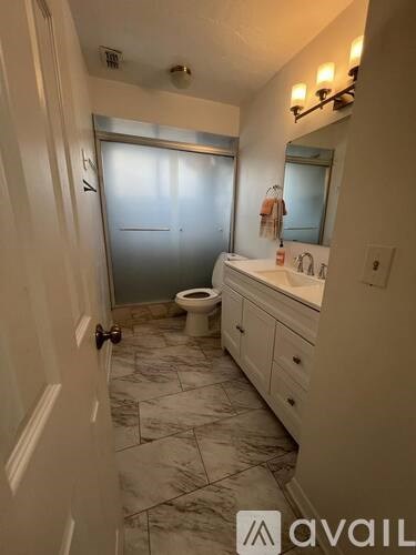 A bathroom with a toilet, sink, and mirror.