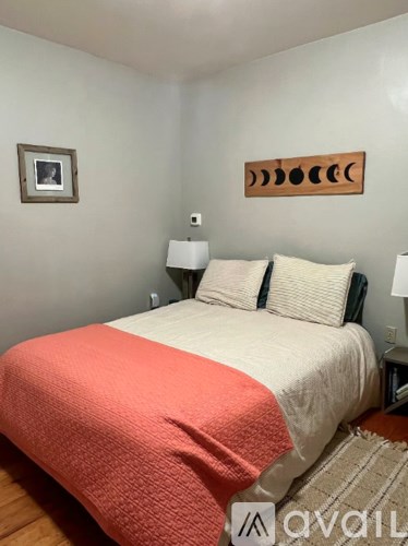 A bedroom with a bed, two pillows, a lamp, and a picture on the wall.