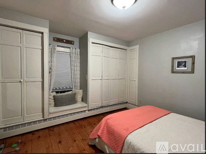 A bedroom with a bed, wardrobe, and a window with curtains.