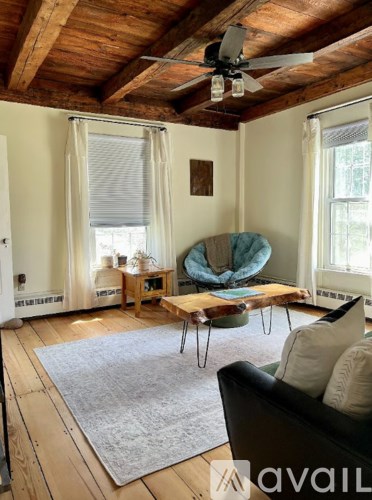 A living room with a black couch and a wooden ceiling fan.