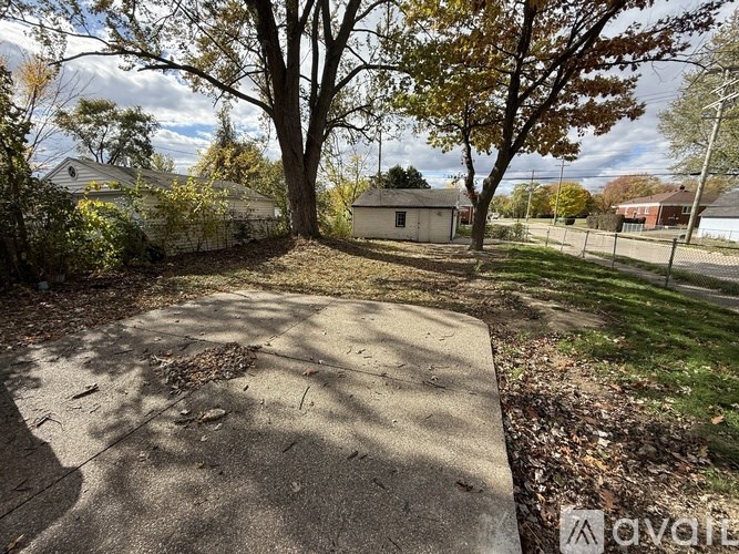 A small building sits in a grassy area with a concrete path leading to it.