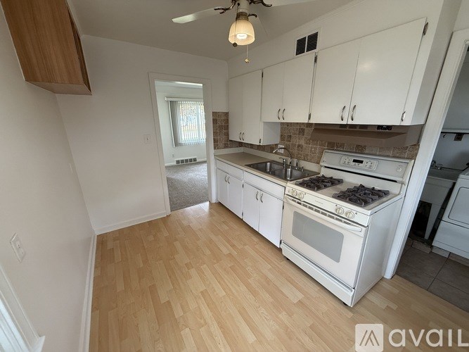 A kitchen with white cabinets and a wooden floor.