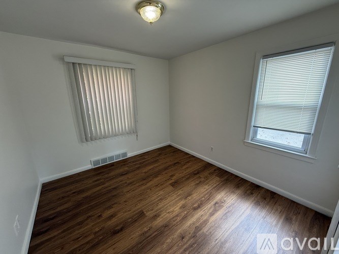 A room with wooden flooring and a window with blinds.