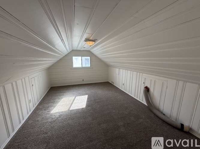 A room with a carpeted floor, white walls, and a window with sunlight streaming in.