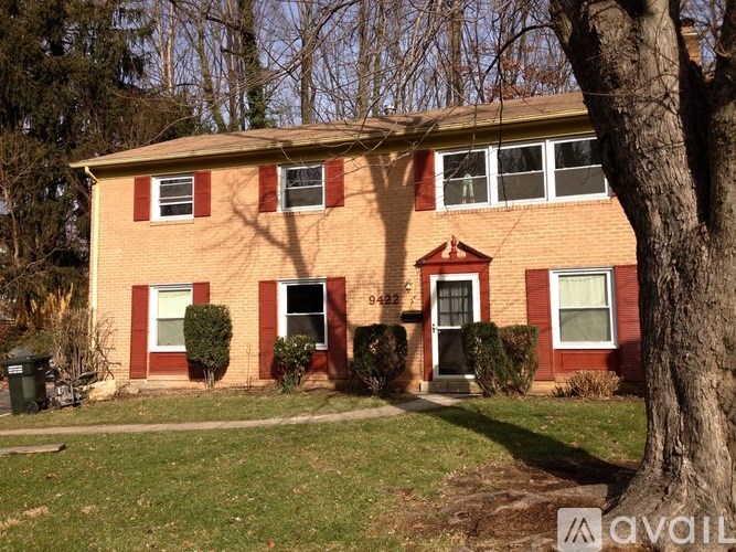 A red brick house with a tree in front.