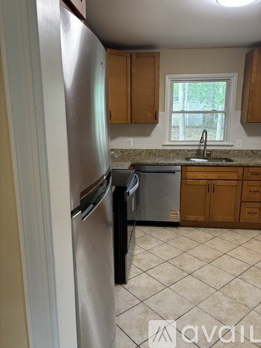 A kitchen with a refrigerator, sink, and cabinets.