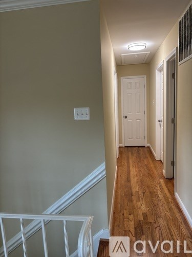 A hallway with a white door and wooden floors.