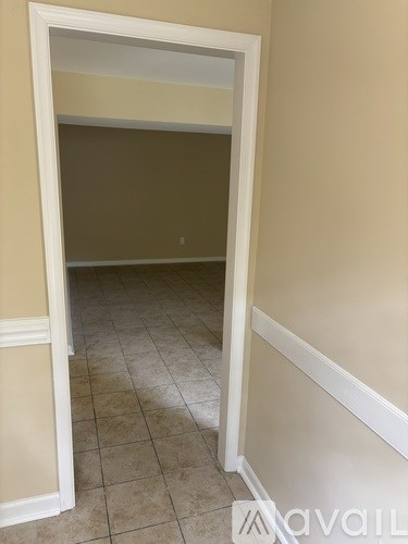 A room with beige walls and tiled floor with a white doorway.