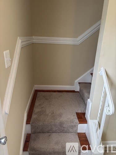 A stairway with a carpeted runner and white balusters.