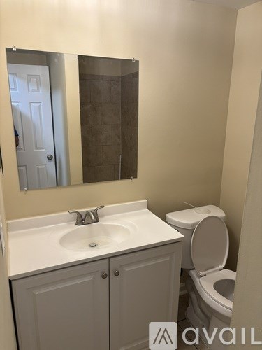 A bathroom with a toilet, sink, and mirror.