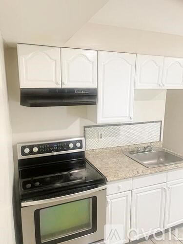 A kitchen with white cabinets and a black stove top oven.