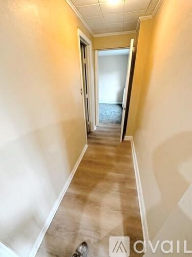 A hallway with a carpeted floor and a door at the end.