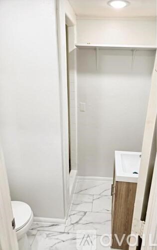 A white toilet in a small bathroom with a marble floor.