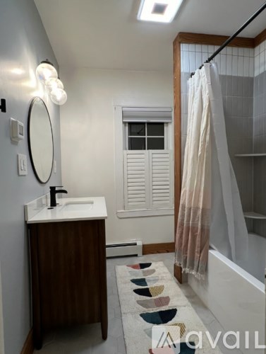 A bathroom with a sink, mirror, and shower.