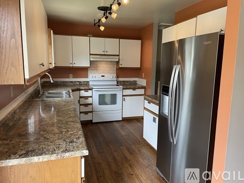 A kitchen with a stainless steel refrigerator and wooden cabinets.