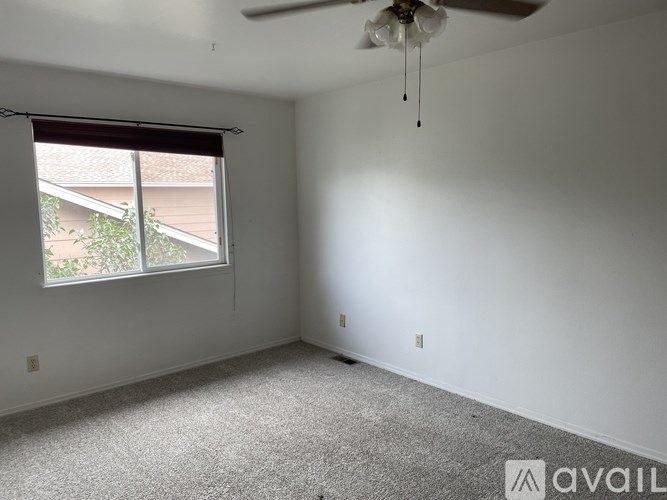 A room with a ceiling fan and a window with blinds.